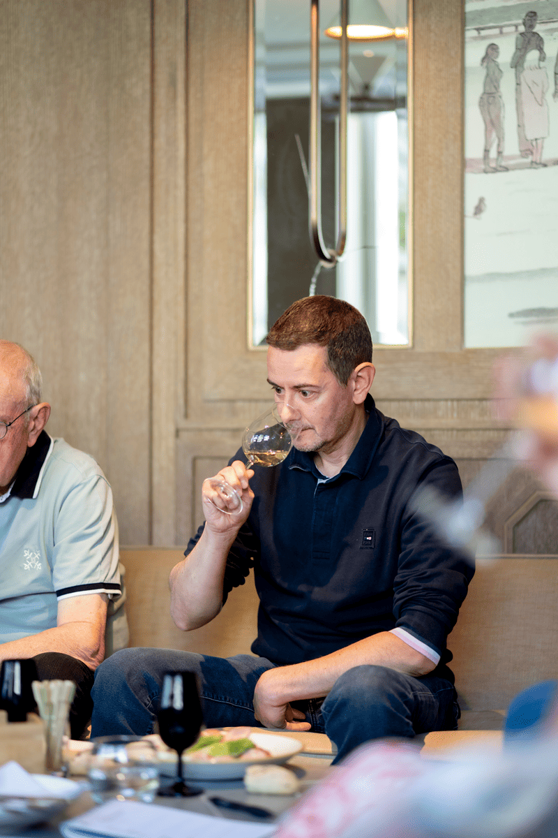 Portrait d'un participant, homme sentant un verre de vin blanc, lors d'un atelier d'oenologie avec son p&egrave;re